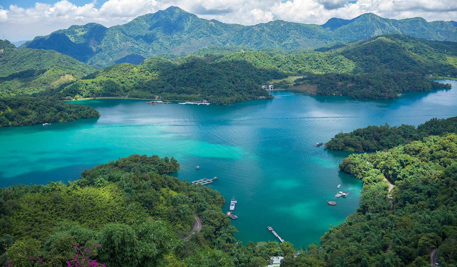 Taiwan Reisen – atemberaubender Blick auf einen smaragdgrünen See umgeben von grünen Bergen und bewaldeten Hügeln, ein perfektes Naturparadies für Wanderer und Naturliebhaber.